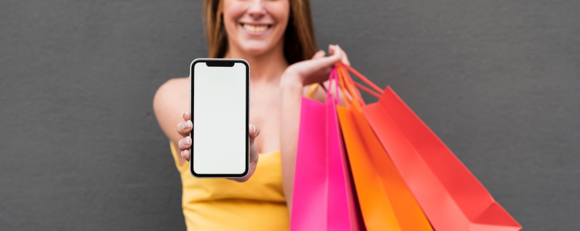 smiling-girl-with-shopping-bags-holding-phone